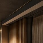 Скрытая ниша для штор в потолке современного интерьера с отделкой из деревянных реек и мягкой подсветкой.